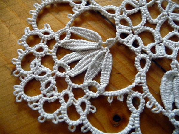 Square white tatting doily with cluny leaf motifs on wooden background by FairyLacefromElena
