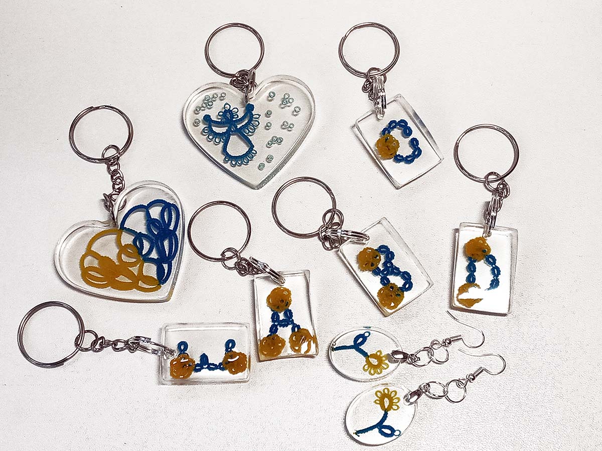 Transparent resin keychains with yellow and blue tatting motifs (letters, hearts, flowers), handmade by FairyLacefromElena