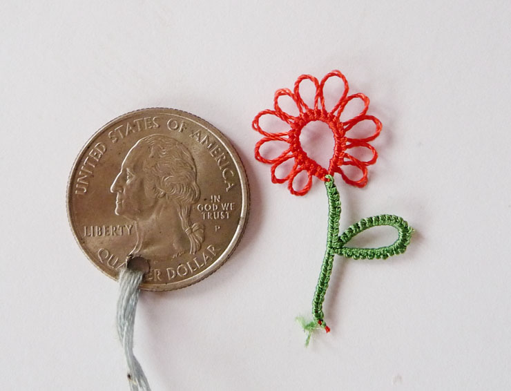 Red tatting lace flower with green stem and leaf shown next to a quarter dollar coin for size comparison, part of the Tatting in resin tutorial series by FairyLacefromElena.