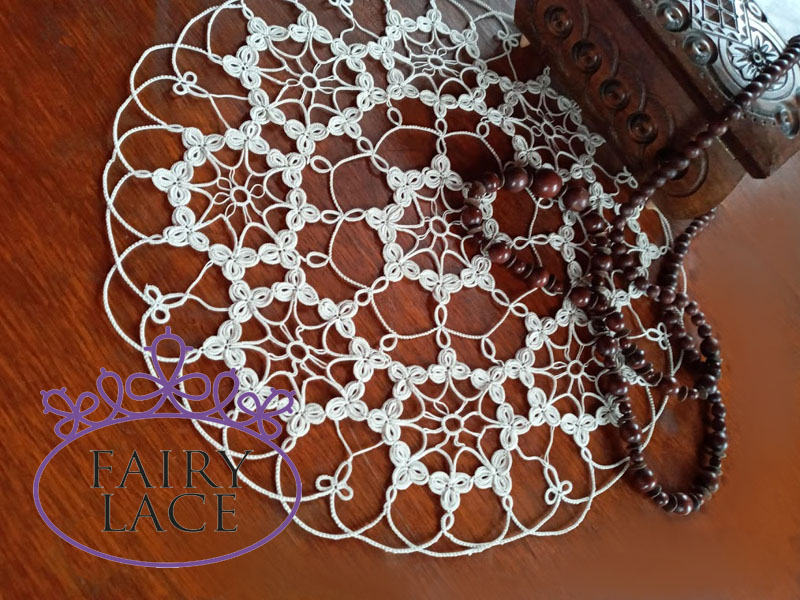 Beige tatting doily with onion rings pattern, displayed on a wooden table beside a carved wooden box and beads by FairyLacefromElena