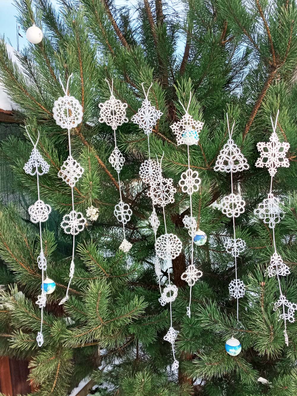 White tatted snowflakes in eight Christmas garlands on pine background — handmade by FairyLacefromElena