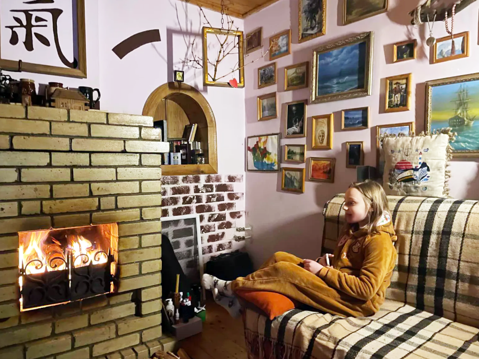 Cozy family gathering by the fireplace in a Ukrainian home, warm evening atmosphere with handmade decor, photo for the blog by FairyLacefromElena