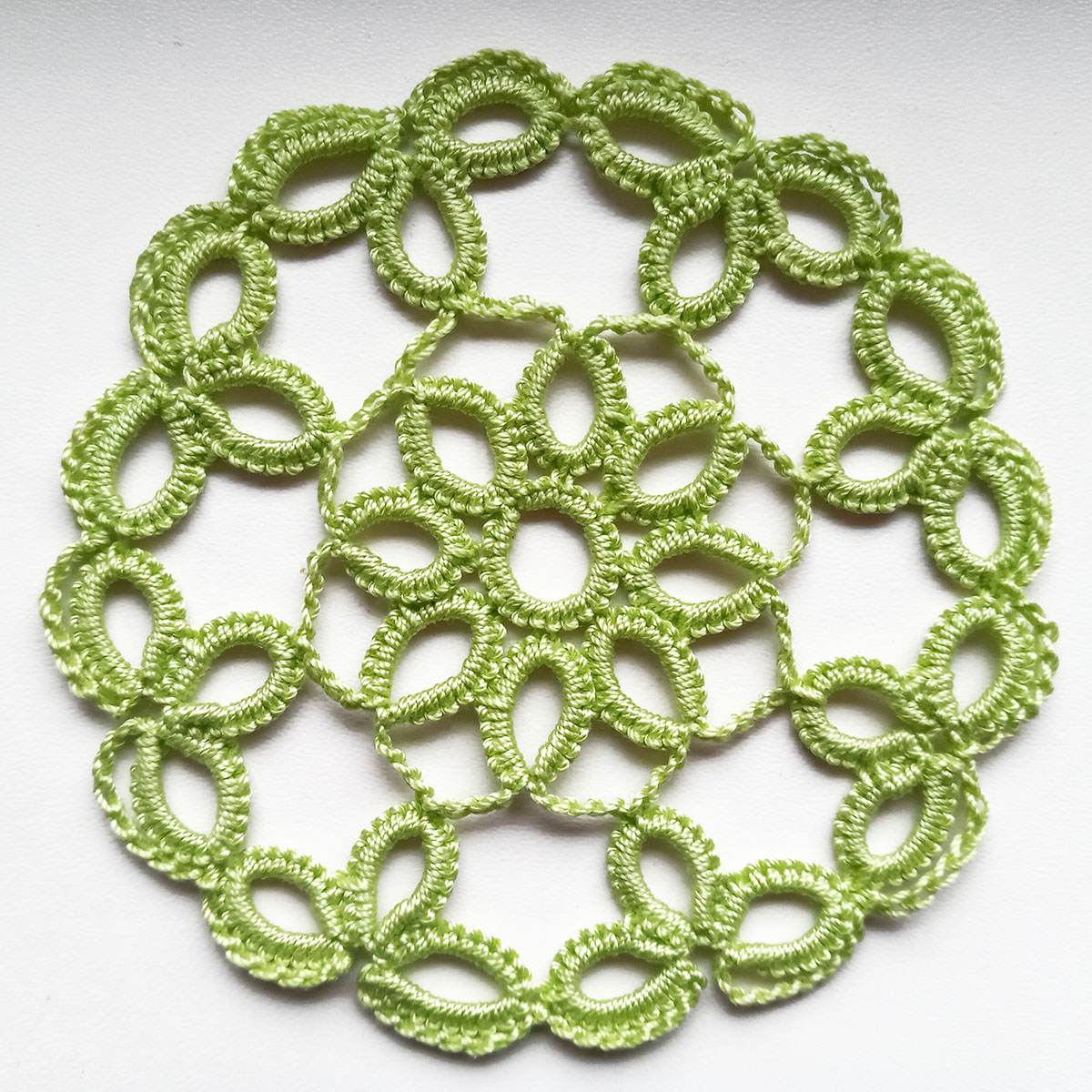 Green lace round coasters in cro-tatting technique.